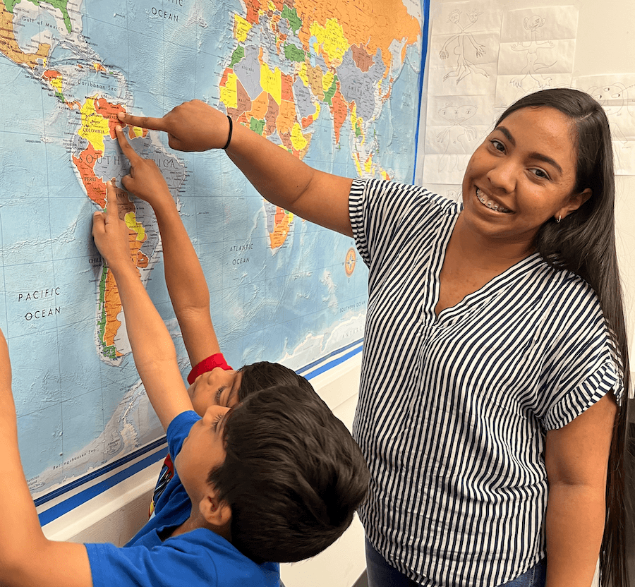 A mother and her sons point to their home country of Venezuela on a map.